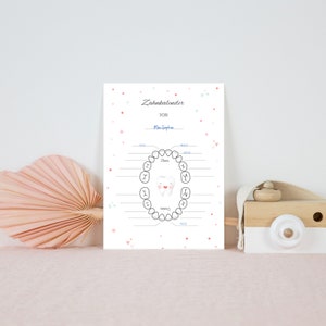 May include: A white tooth chart with a cartoon tooth smiling. The chart is titled "Zahnkalender" and has a space for a name. The chart is decorated with pink and blue hearts and stars.