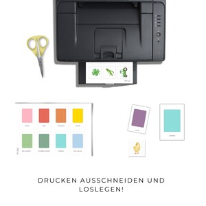 K&ouml;nnte beinhalten: Ein Drucker mit bedruckten Karten mit farbigen Quadraten, Illustrationen und dem Text "DRUCKEN AUSSCHNEIDEN UND LOSLEGEN!". Eine gelbe Schere ist ebenfalls zu sehen.