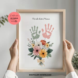 Puede incluir: Descarga digital imprimible de un diseño de arte de huellas de manos para el Día de la Madre. El diseño presenta dos huellas de manos en verde y rosa, un ramo de flores y el texto "Para la mejor mamá".