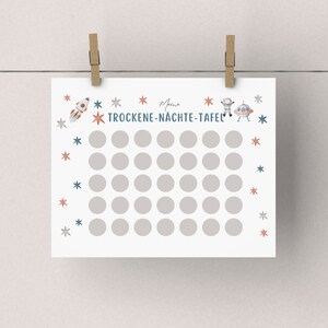 K&ouml;nnte beinhalten: Ein wei&szlig;er, druckbarer Chart mit Weltraum-Motiv. Der Chart hat den Text "Meine Trocken-N&auml;chte-Tafel" und eine Illustration von einer Rakete, einem Astronauten und einem UFO. Der Chart hat 42 Kreise, um trockene N&auml;chte abzuhaken.