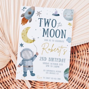 May include: A blue and white invitation card featuring a cartoon astronaut holding a yellow crescent moon balloon. The card reads "Two the Moon" and "Robert's 2nd Birthday".