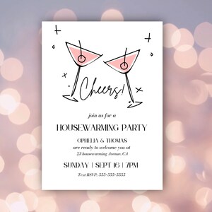 May include: A white invitation with black text and a hand-drawn illustration of two pink martini glasses. The text reads "Cheers!" and "Join us for a Housewarming Party". The invitation also includes the names "Ophelia & Thomas", the date "Sunday, Sept 16", the time "7PM", and the address "23 Housewarming Avenue, CA".