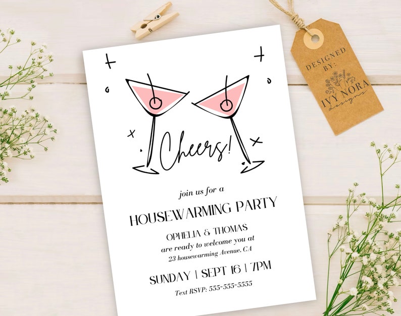 May include: A white invitation card with black text and a pink illustration of two martini glasses. The text reads "Cheers!" and "Join us for a Housewarming Party". The invitation is for Ophelia & Thomas on Sunday, September 16th at 7pm. The text RSVP is 555-555-5555.