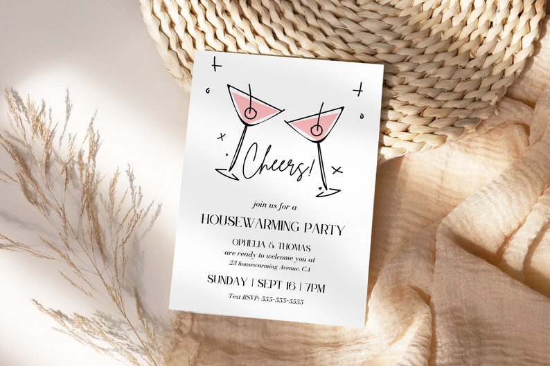 May include: A white card with black text and a pink and black illustration of two martini glasses. The text reads "Cheers!" and "Join us for a Housewarming Party, Ophelia & Thomas are ready to welcome you at 23 Housewarming Avenue, CA, Sunday, Sept 16, 7PM, Text RSVP: 533-555-5555".