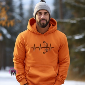May include: Orange hoodie with a black heartbeat graphic featuring a bow and arrow.