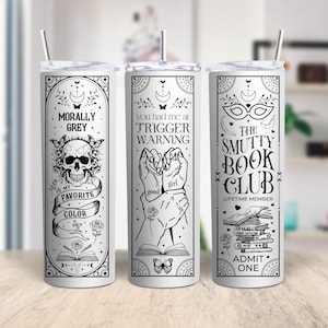 May include: Three stainless steel tumblers with black and white designs. The first tumbler has a skull and crossbones with the text "Morally Grey is my favorite color". The second tumbler has a hand holding a book with the text "You had me at Trigger Warning". The third tumbler has a mask and the text "The Smutty Book Club Lifetime Member Admit One".