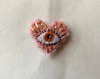 Eye heart shaped mini pin/brooch/button with metallic gold accents//hand embroidered witchy/whimsical pink felt fiber art pin