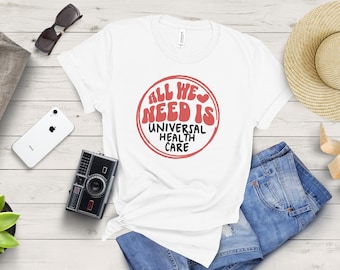 May include: White t-shirt with a red circle graphic that says "All We Need Is Universal Health Care" in a retro font.
