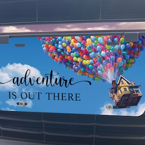 May include: A blue and white license plate with a house and colorful balloons floating in the sky. The text "adventure is out there" is printed on the plate.