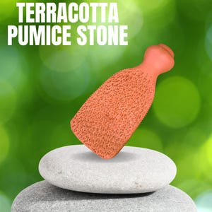 Puede incluir: Piedra pómez de terracota, una piedra rugosa de color naranja con una superficie texturizada, descansando sobre dos piedras lisas de color gris.