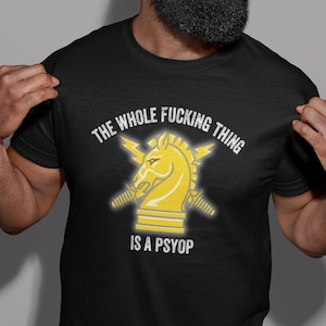 May include: Black t-shirt with a yellow knight chess piece graphic and the text "THE WHOLE FUCKING THING IS A PSYOP".