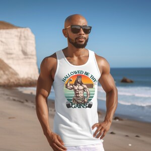 May include: White tank top with a retro-style graphic of a muscular Jesus figure lifting a barbell with the text "HALLOWED BE THY GAINS".