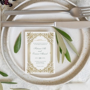 May include: A wedding invitation card with gold ornate borders and text, placed on a white plate with a fork and knife. The invitation includes the names Fatima Ali and Osman Ahmed, with the date August 28, 2024.