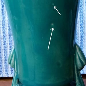 May include: A teal green ceramic vase with two handles. The vase has three small white spots on the surface.
