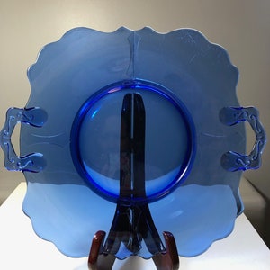 May include: A cobalt blue glass serving tray with two handles. The tray has a scalloped edge and a raised center.