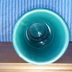 May include: A teal ceramic planter with a smooth, glossy finish. The planter is empty and ready for a plant.