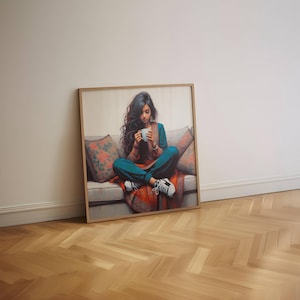 May include: A framed art print shows a person seated on a sofa, holding a white mug. The person wears teal trousers, a rust-coloured top, and white trainers. The sofa has floral cushions and a red patterned blanket. The artwork is in a wooden frame.