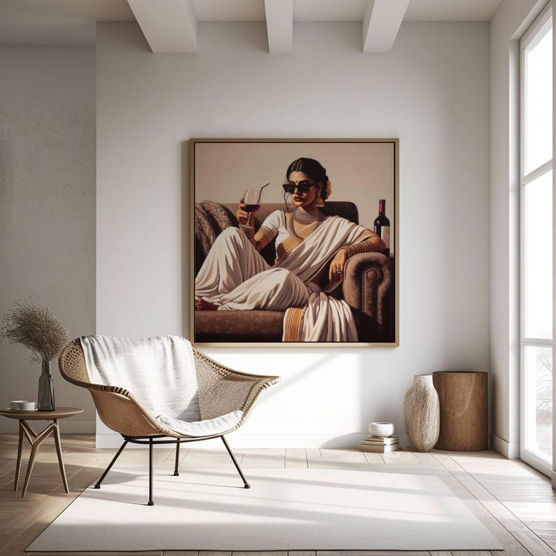 May include: A framed artwork depicts a person in a white sari, sunglasses, and jewelry, holding a glass of wine. The painting hangs above a brown sofa. A woven chair and side table with a vase are in the foreground, creating a stylish interior scene.