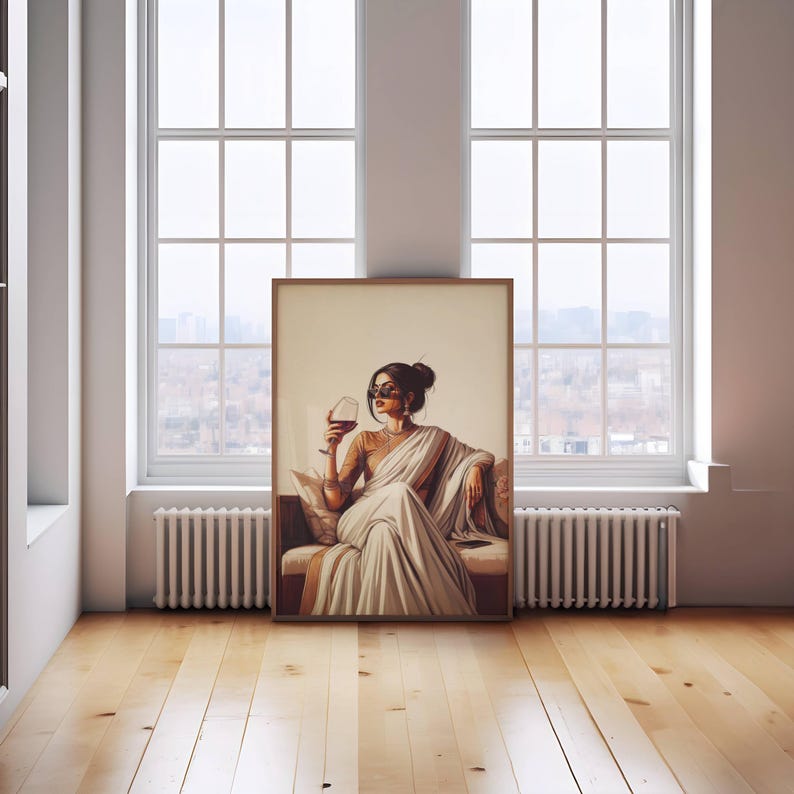 Puede incluir: Una impresi&oacute;n art&iacute;stica enmarcada representa a una persona con un sari blanco sosteniendo una copa de vino tinto. La obra de arte est&aacute; ambientada sobre un fondo neutro, con la persona usando gafas de sol. La impresi&oacute;n se exhibe en una habitaci&oacute;n con grandes ventanas y pisos de madera.
