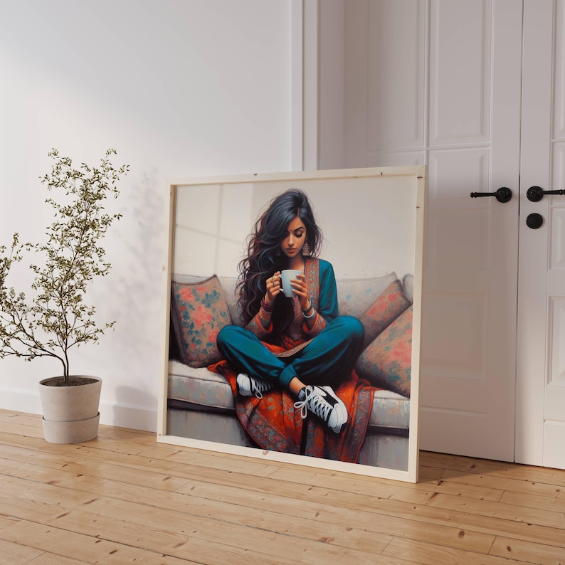 May include: A framed artwork shows a person seated on a sofa, holding a white mug. The person wears teal clothing and white trainers. The sofa has floral patterned cushions and a red patterned throw. The artwork leans against a white wall.
