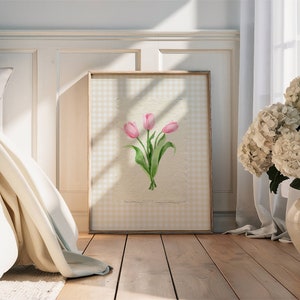 Pode incluir: Uma impress&atilde;o de arte emoldurada apresentando uma ilustra&ccedil;&atilde;o em aquarela de tr&ecirc;s tulipas cor-de-rosa com caules e folhas verdes, centralizada em um fundo de papel off-white texturizado com uma borda de padr&atilde;o xadrez vichy amarelo claro e branco.