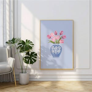 May include: A framed art print featuring a blue vase with white floral designs, holding pink tulips against a light blue background. The artwork is encased in a gold frame, adding a touch of elegance to the floral arrangement.