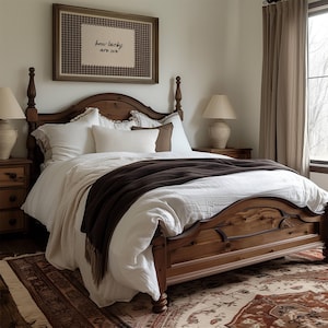 May include: A wooden four-poster bed with white bedding and a dark brown throw blanket. The bed is in a bedroom with a framed artwork that reads "how lucky are we". Two bedside lamps and a patterned rug complete the cozy bedroom setting.