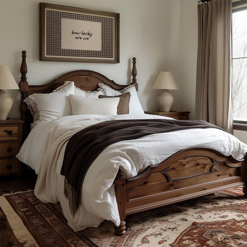 May include: A wooden four-poster bed with white bedding and a dark brown throw blanket. The bed is in a bedroom with a framed artwork that reads "how lucky are we". Two bedside lamps and a patterned rug complete the cozy bedroom setting.