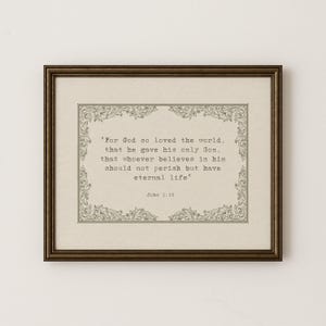 Puede incluir: Impresión enmarcada con una cita de Juan 3:16, con un borde decorativo. El texto está en una fuente serif clásica sobre un fondo crema. El marco es de color marrón oscuro y cálido.