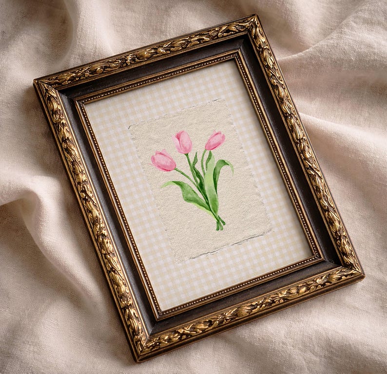 Pode incluir: Uma moldura retangular com uma borda ornamentada em castanho escuro e dourado. No interior, um fundo de xadrez vichy bege claro apresenta uma ilustra&ccedil;&atilde;o em aguarela centrada de tr&ecirc;s t&uacute;lipas cor-de-rosa com caules e folhas verdes em papel texturado.