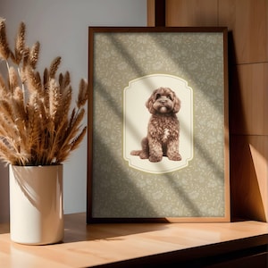 May include: A framed print featuring a brown dog illustration. The dog is centered on a cream-colored, decorative frame against a floral patterned background. The frame is brown and the print is displayed on a wooden surface.