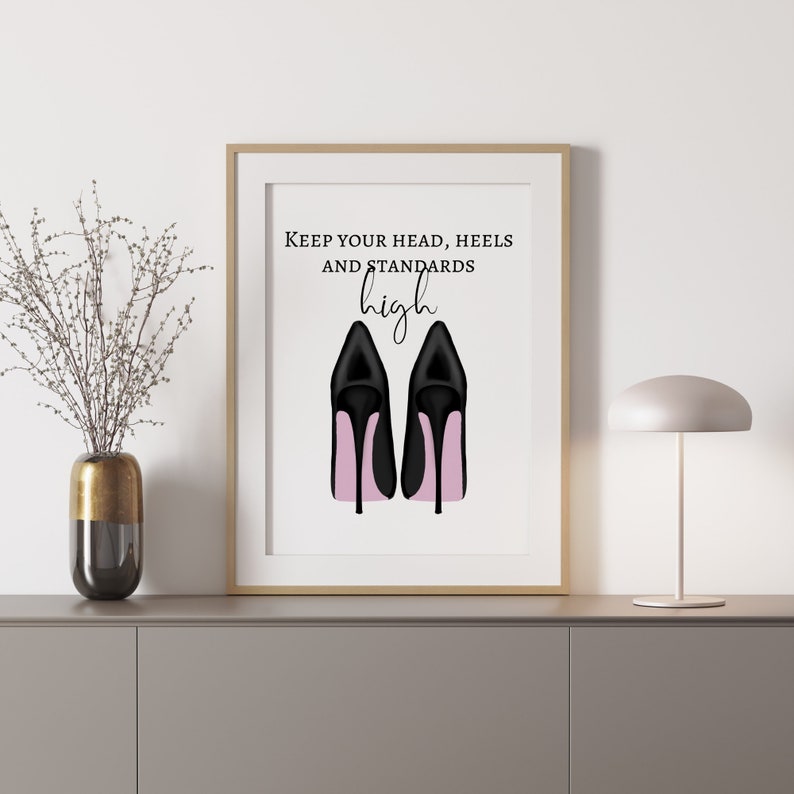 May include: Framed art print featuring a pair of black high heels with pink soles. The artwork includes the text "Keep your head, heels and standards high" in black script and block letters. The print is displayed in a gold frame.
