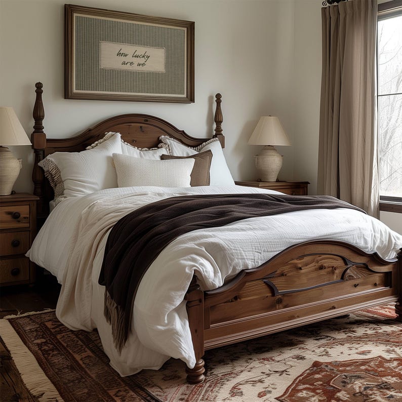 May include: A bedroom scene featuring a wooden bed with a dark brown blanket and white bedding. A framed artwork with the text "how lucky are we" hangs above the bed. Two bedside lamps and a patterned rug complete the cozy, inviting space.