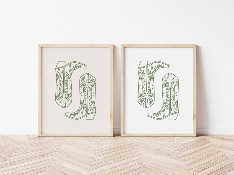 May include: Two framed prints each display a green line drawing of a cowboy boot. The boots are in a minimalist style with decorative stitching and the word "Evelyn" on the boot. One print has a cream background, the other a white background.