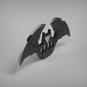 May include: A black metal bat-shaped keychain with a crown design and a gear-like pattern on the wings.