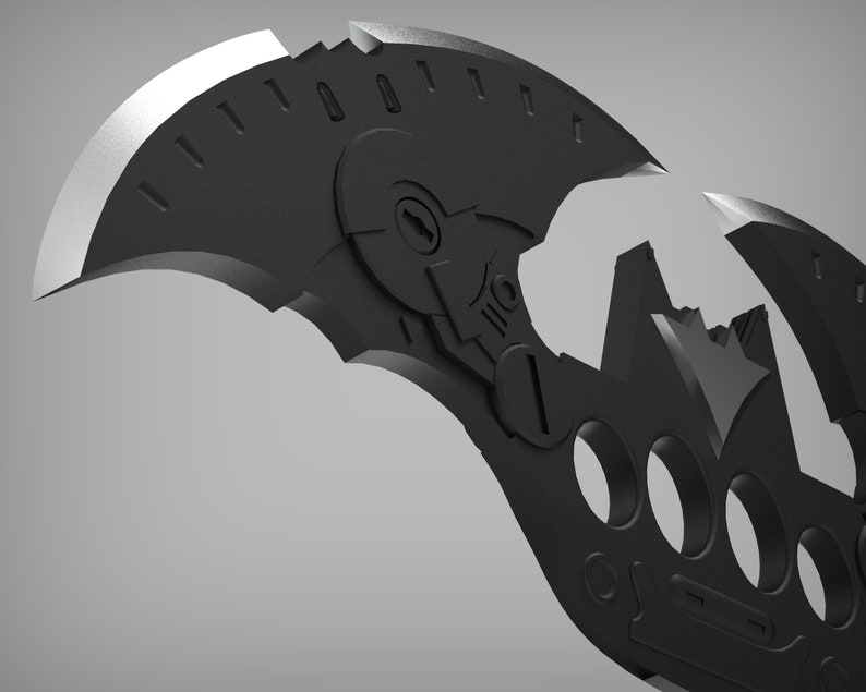 May include: A black metal batarang with a detailed design, featuring a sharp blade and a series of holes. The batarang is split into two pieces, revealing a bat symbol in the center.