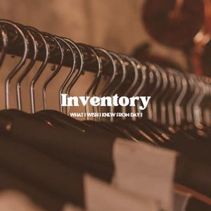 May include: A row of metal clothing hangers with black tops, hanging on a clothing rack. The word "Inventory" is displayed in white text, with the text "WHAT I WISH I KNEW FROM DAY 1" below it.