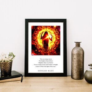 May include: A black framed print featuring a fiery orange and yellow image of a woman standing in a circle of moons. The text below the image reads "I'm an orange moon I'm brighter than before Brighter than ever before I'm an orange moon and I shine so bright Cause I reflect the light of my sun."  ERYKAH BADU