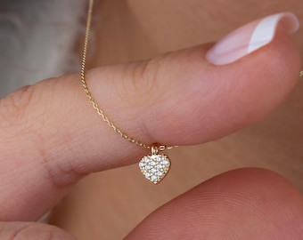May include: A delicate gold chain necklace with a small heart pendant encrusted with tiny sparkling diamonds.
