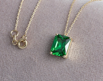 May include: A gold chain necklace with a green emerald-cut gemstone pendant.