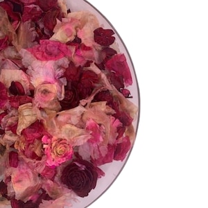 May include: A clear glass bowl filled with dried potpourri. The potpourri includes a mix of pink, red, and beige dried flowers and petals. The arrangement is set against a white background.