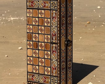 May include: A tall, rectangular wooden box with intricate inlaid geometric patterns in shades of brown, red, and black. The box has a hinged door with a metal clasp and a dark border.