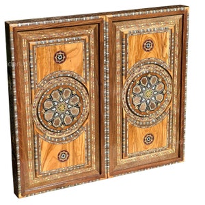 Könnte beinhalten: Zwei Holzfaltwände mit komplizierten geometrischen Mustern, die in Holz eingelegt sind. Die Muster sind in Braun-, Beige- und Weißtönen gehalten.