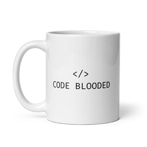 May include: White ceramic coffee mug with black text that reads "</> CODE BLOODED".