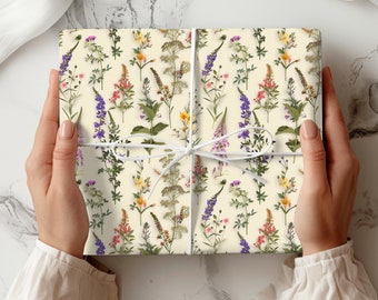 May include: A gift wrapped in white paper with a floral pattern. The paper features a repeating pattern of various wildflowers in shades of purple, pink, yellow, and green.