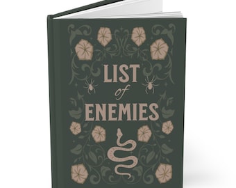 May include: A dark green journal with a floral design and the text "List of Enemies" in a light pink font. The journal features a snake, spiders, and flowers.