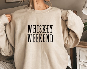 May include: A beige sweatshirt with the text "WHISKEY WEEKEND" printed in black.