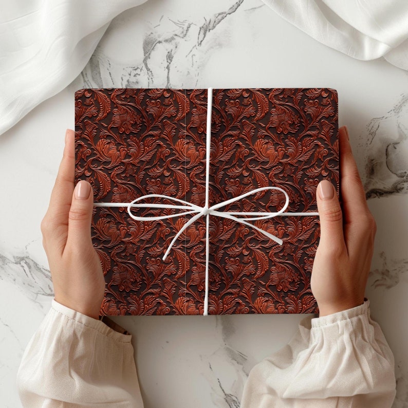 May include: A brown gift box with a white ribbon tied in a bow. The box is wrapped in paper with a floral pattern.