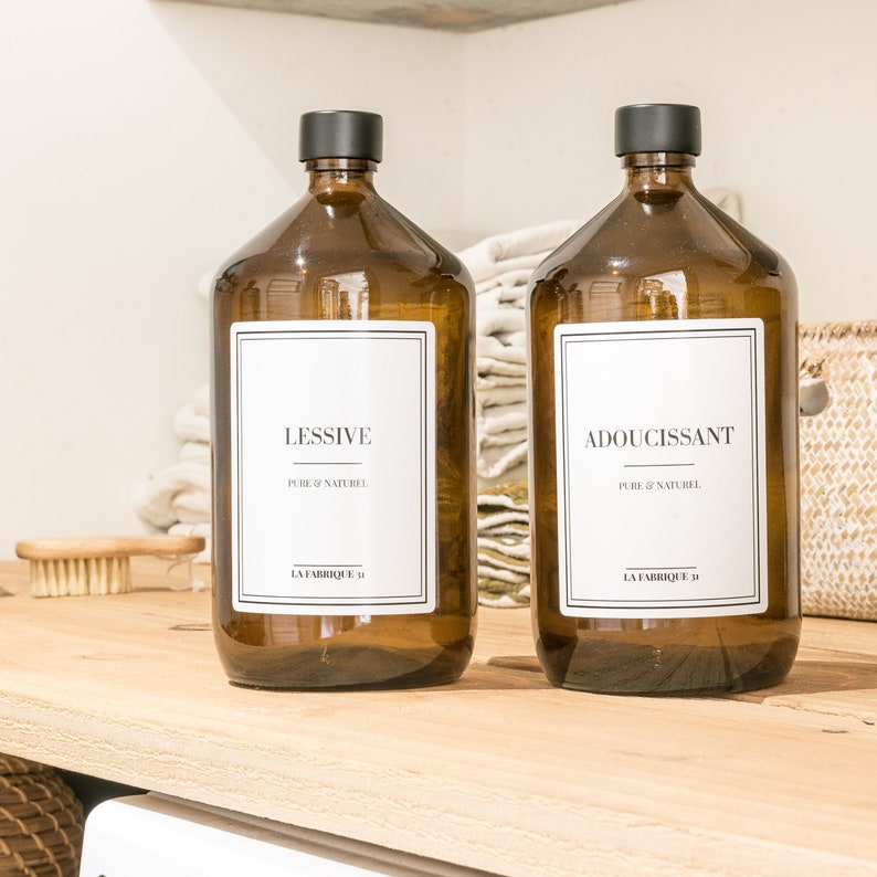 May include: Two brown glass bottles with black caps and white labels. The labels say "Lessive Pure & Naturel La Fabrique D" and "Adoucissant Pure & Naturel La Fabrique D".