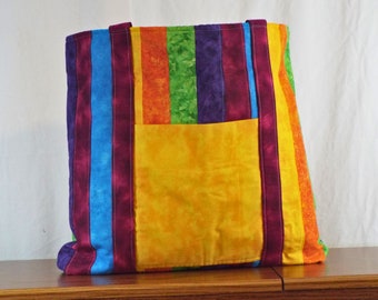 May include: A colorful striped tote bag with a large yellow pocket. The bag is made of fabric and has a quilted design.